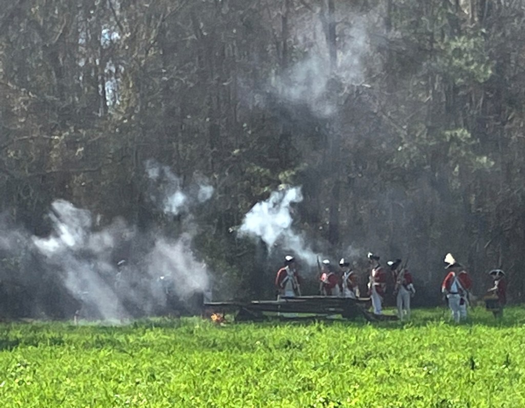 Reenactors firing at the edge of the woods in a cloud of smoke