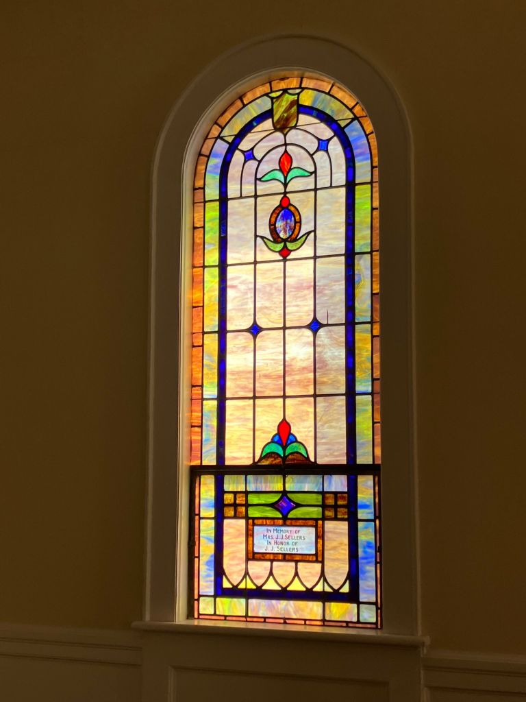 Arched stained glass window glowing in the sanctuary