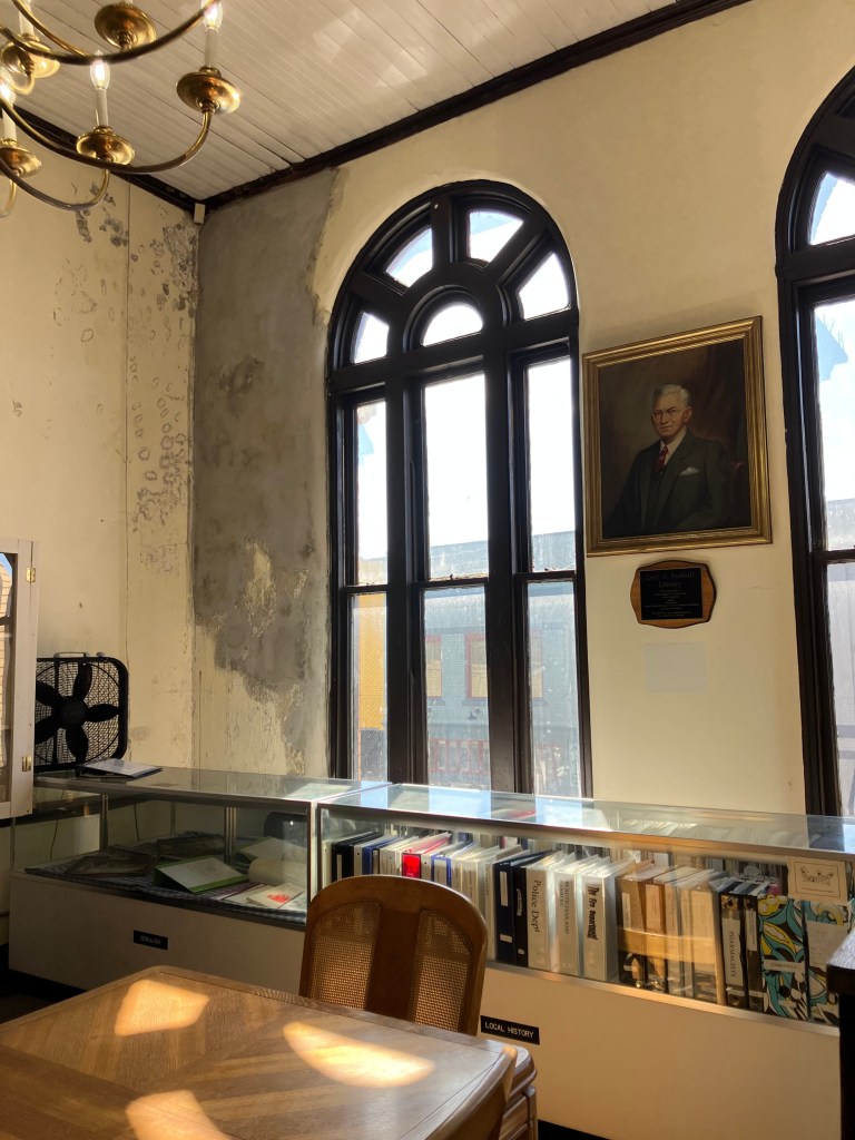 Upstairs room of the Cherryville Historical Museum with tall arched windows and a portrait