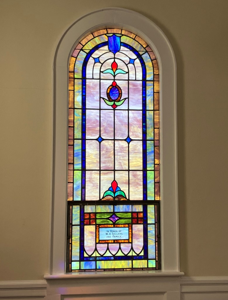 Tall arched stained glass window inside Mary's Grove Community Church