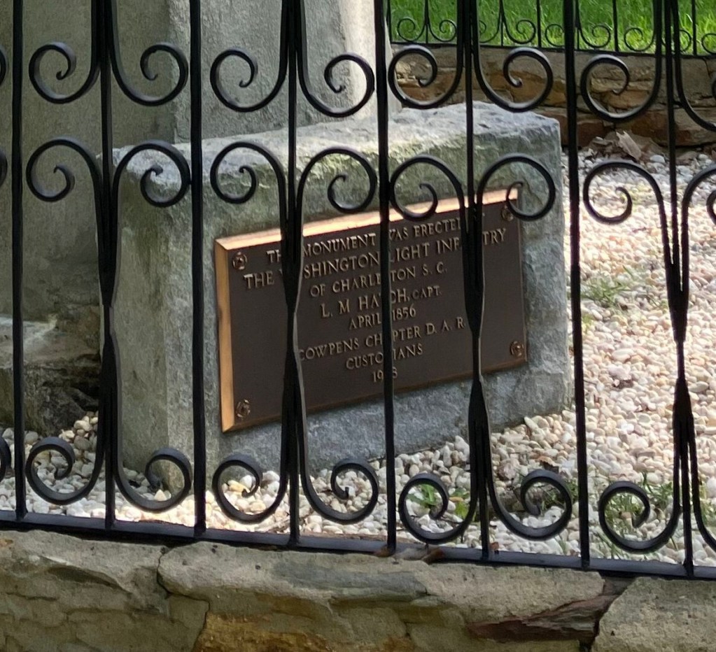 Bronze plaque on the Washington Light Infantry monument seen through the iron fence