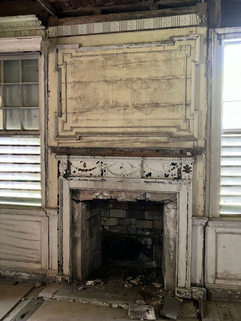 Fireplace with a carved overmantel panel between shuttered windows