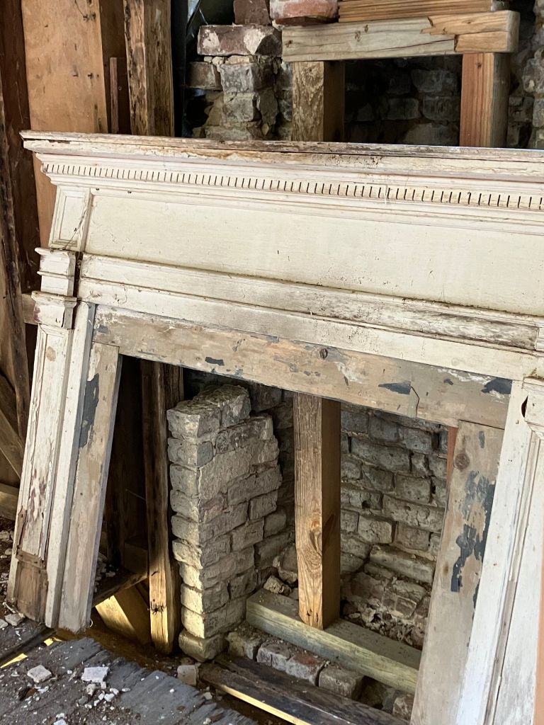 Old mantel and bricked fireplace in a room of the Tibwin house