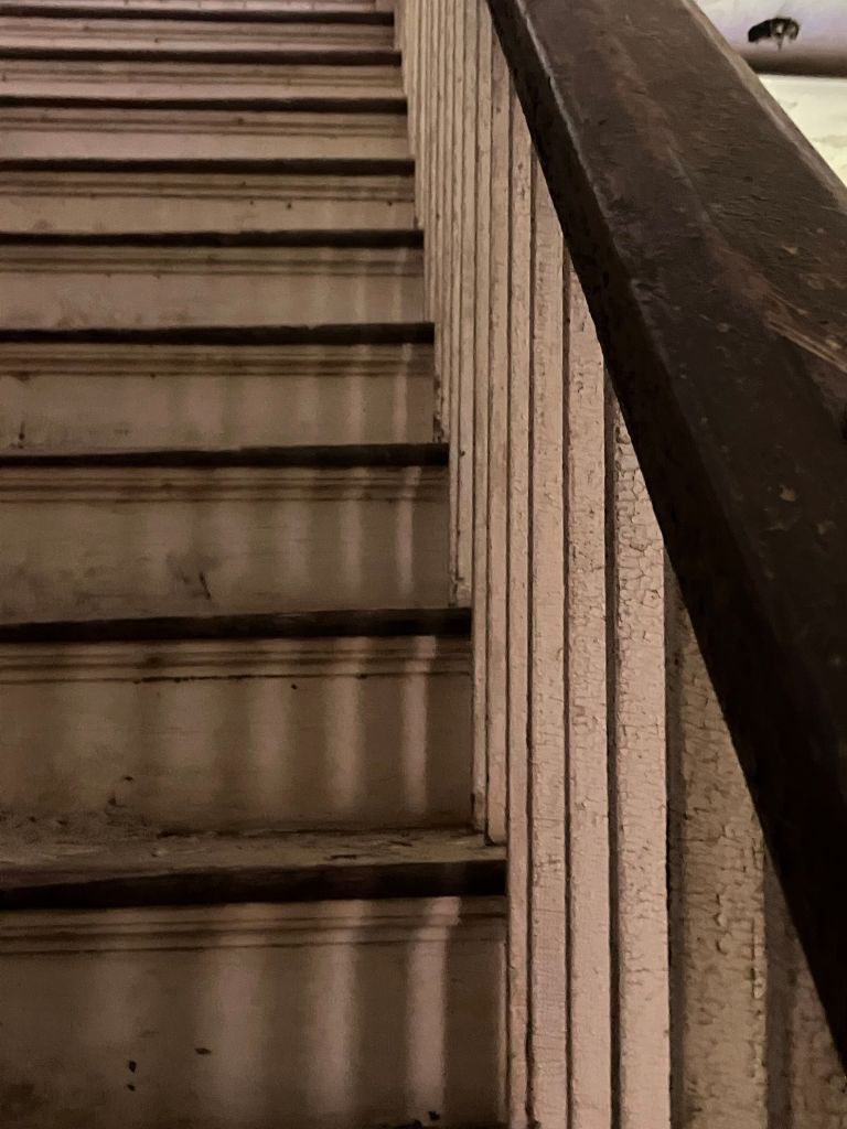 Steep wooden stairs with a dark handrail