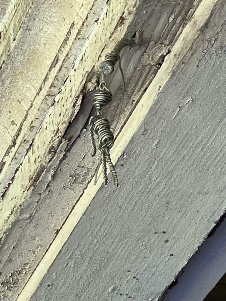Twisted wire hanging from a painted porch beam