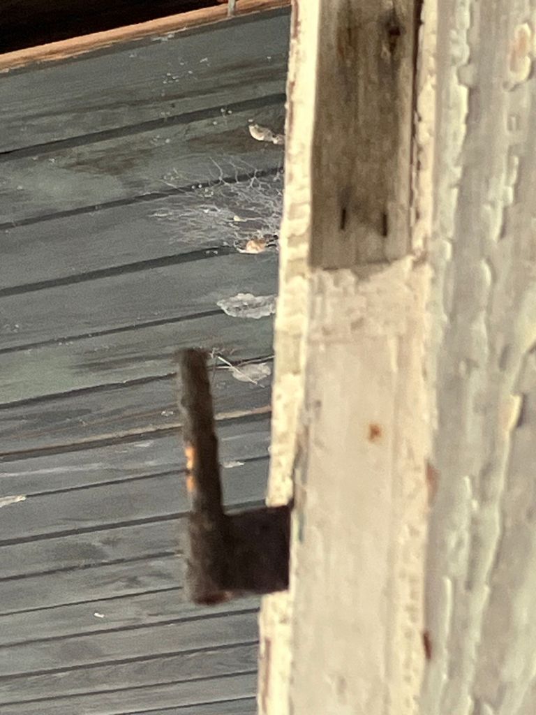 Rusted iron hinge on a weathered door frame at Tibwin