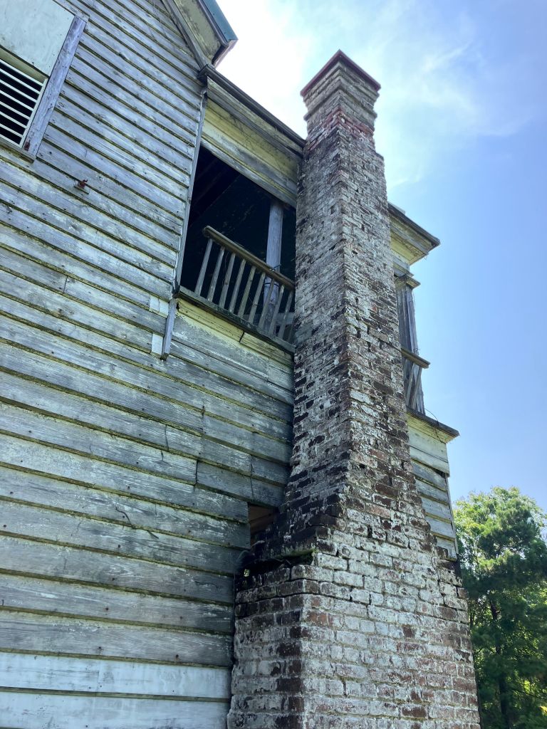 Weathered clapboards and brick chimney on the side of the Tibwin house