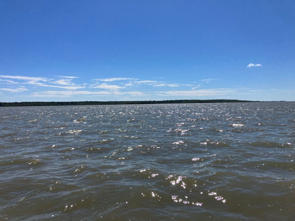 Low island on the horizon seen from the boat across choppy water