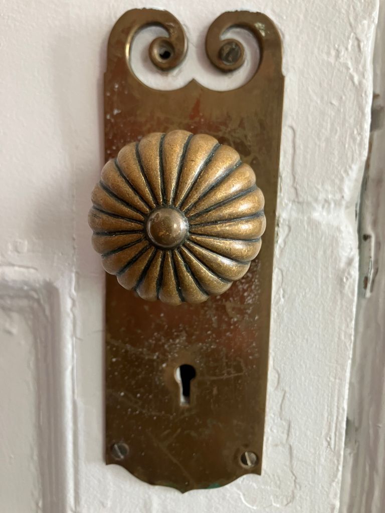 Ornate brass doorknob and keyhole plate on an old hotel door
