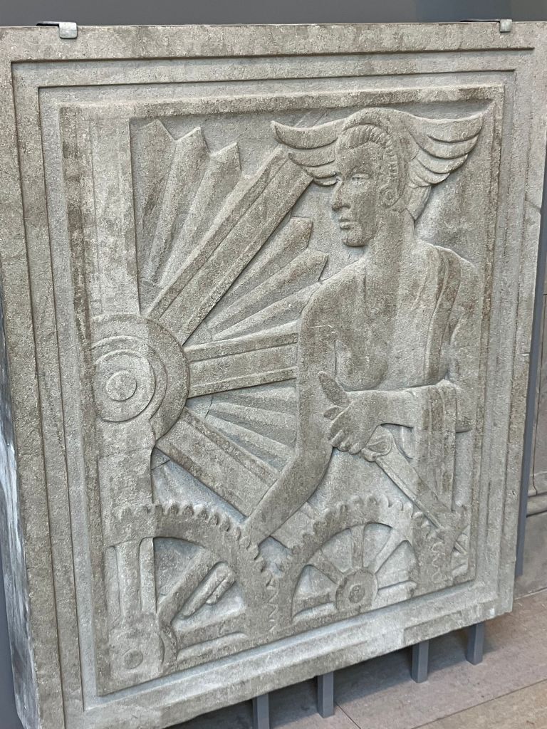 Carved stone art deco relief panel of a figure with a sunburst