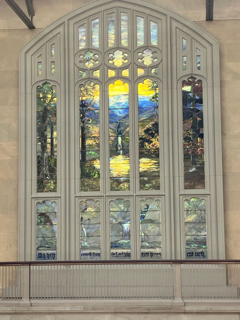 Large stained glass window with a landscape scene in a museum gallery