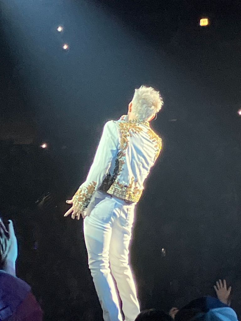 Adam Lambert in a light suit striding along the catwalk