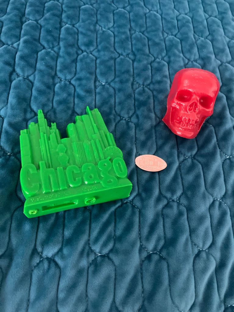 A green molded Chicago skyline and a red molded skull from Mold-A-Rama machines
