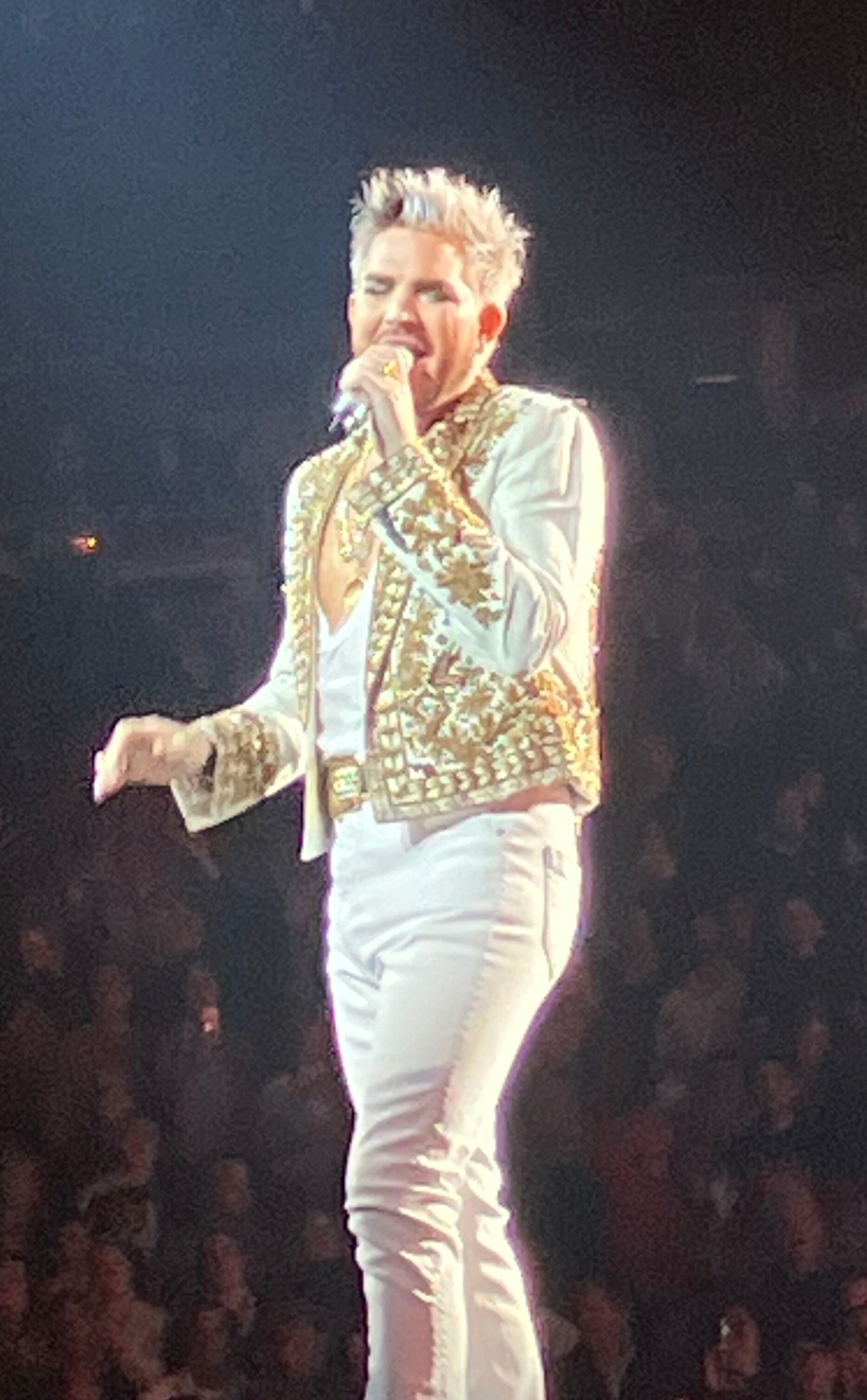Adam Lambert singing in a gold jacket