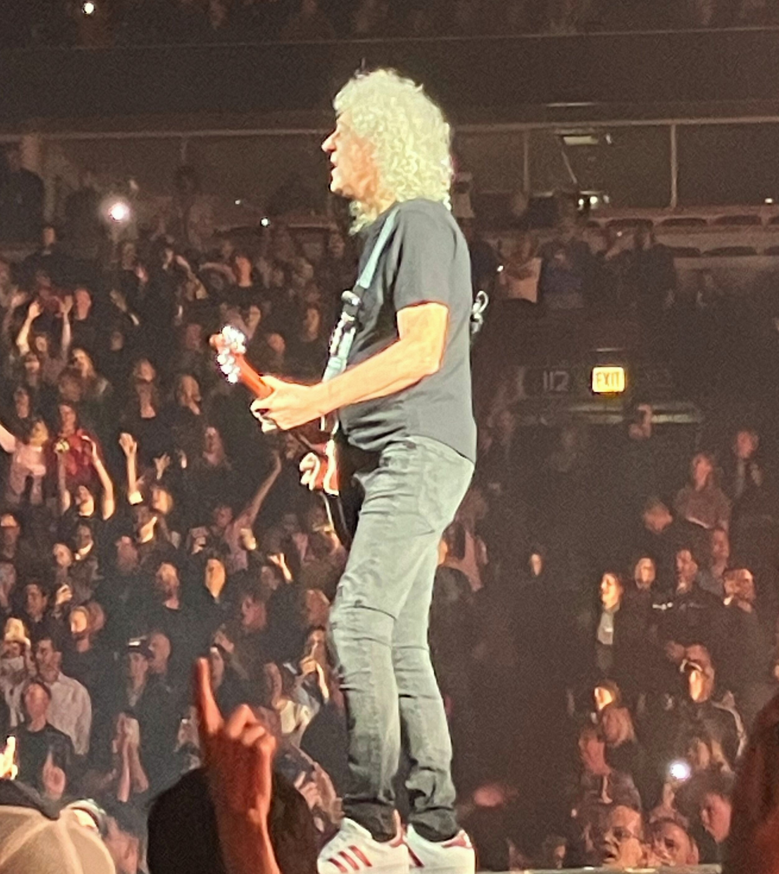 Brian May playing guitar at the front of the stage