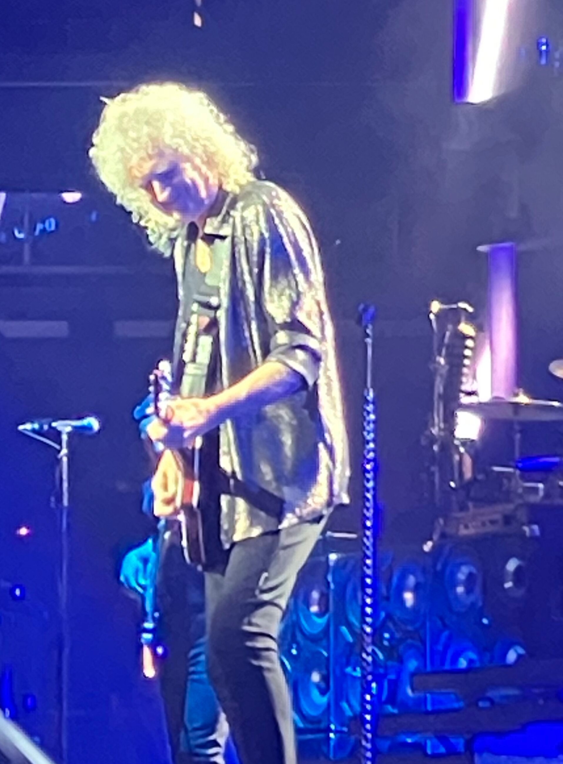 Brian May playing guitar under the stage lights