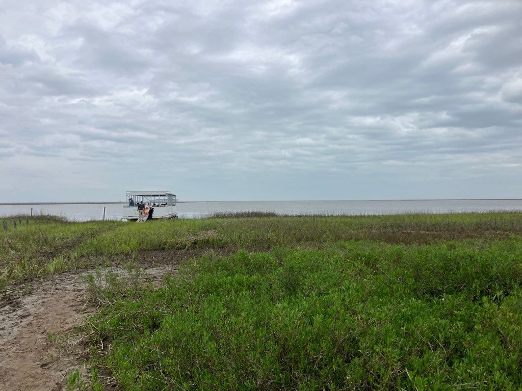 Path through the grass toward the water and an old structure