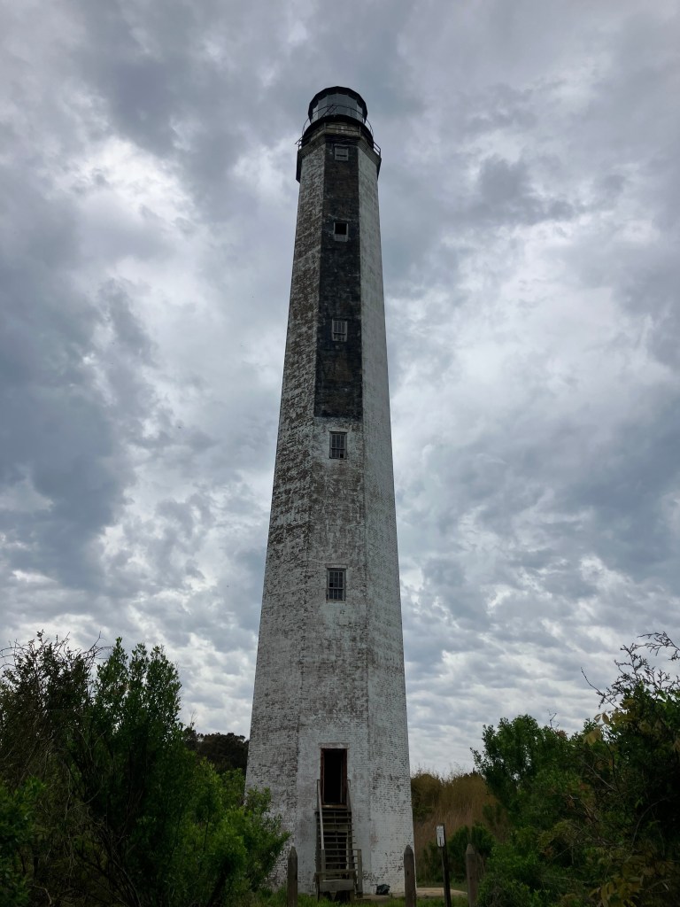 The tall octagonal 1858 Cape Romain Lighthouse under dramatic clouds