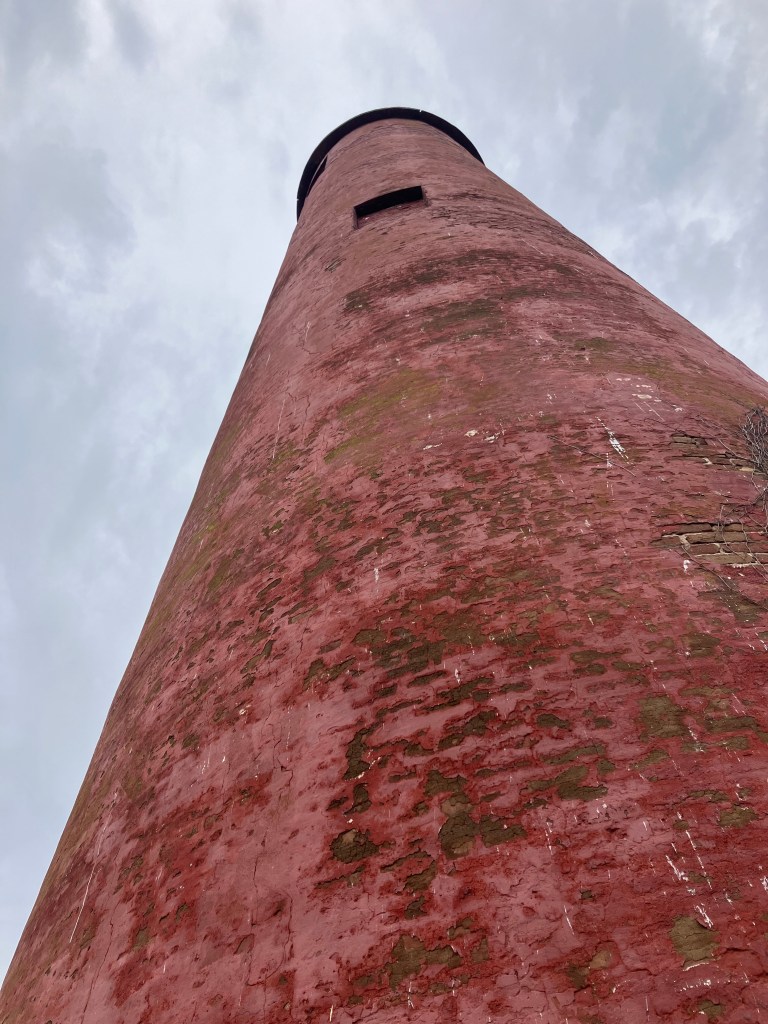 Red brick 1827 lighthouse tower against a gray sky