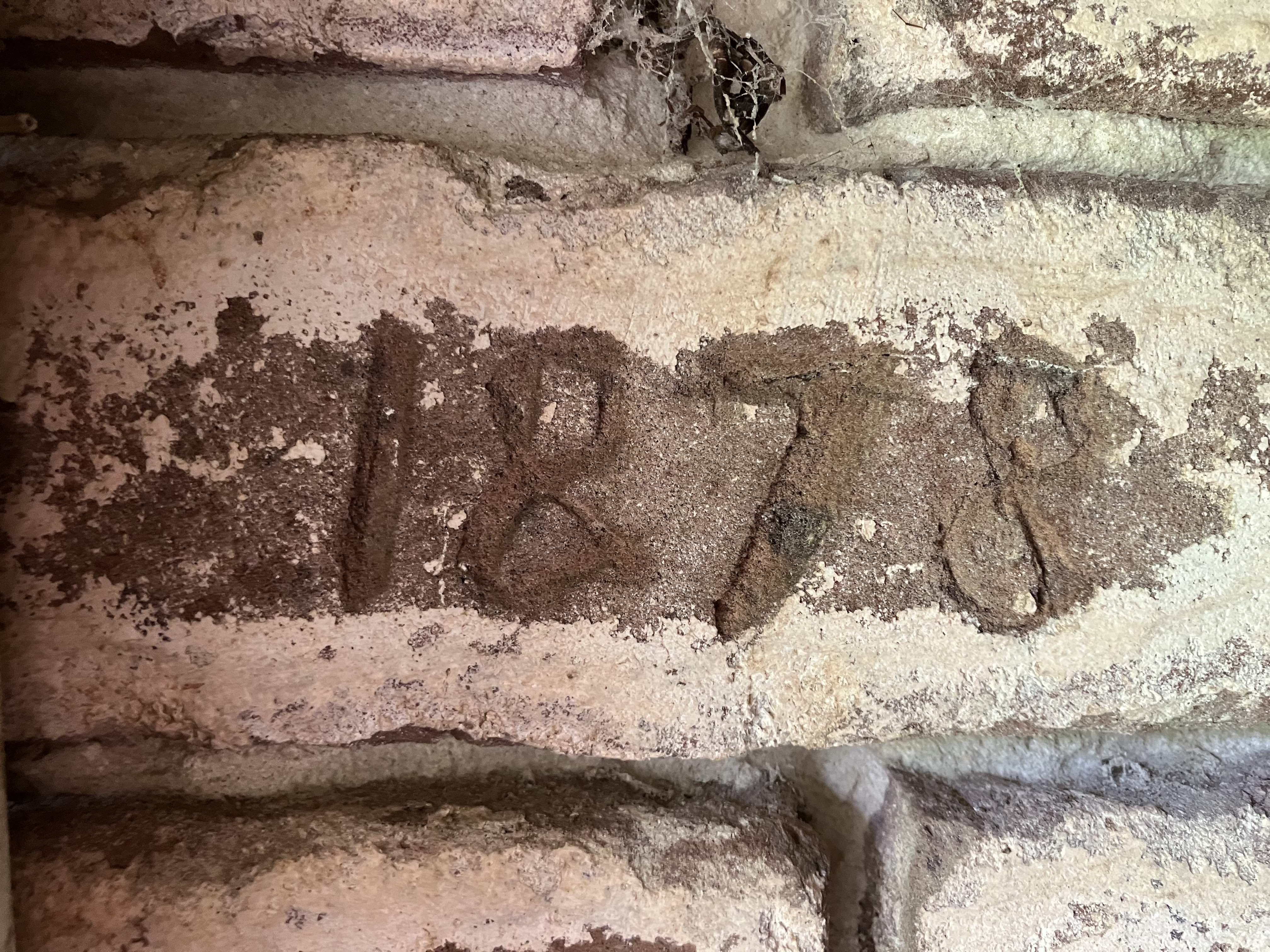 The carved date 1878 in a weathered brick