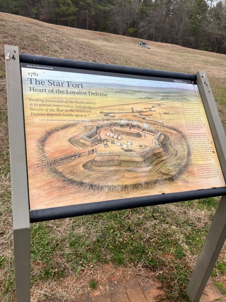 Park sign titled The Star Fort, Heart of the Loyalist Defense, with a painting of the earthen star-shaped fort