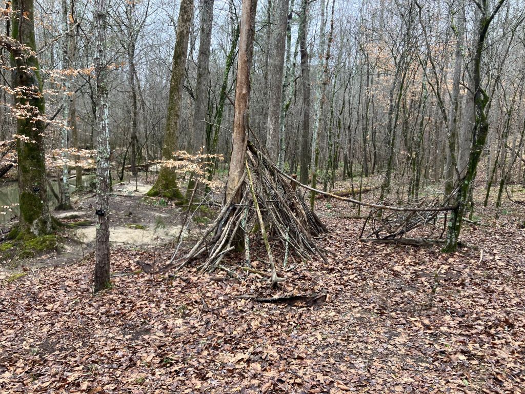 Teepee-shaped shelter of leaning sticks in the woods