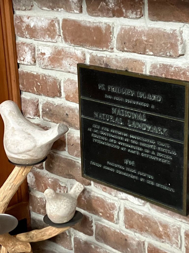 Plaque on the brick wall about St. Phillips Island with carved bird decorations