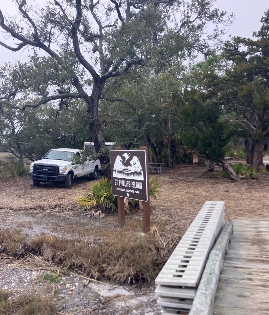 Truck and sign at the St. Phillips Island landing under live oaks