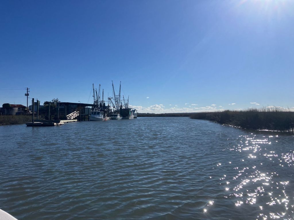 Shrimp boats docked along a sunlit tidal creek