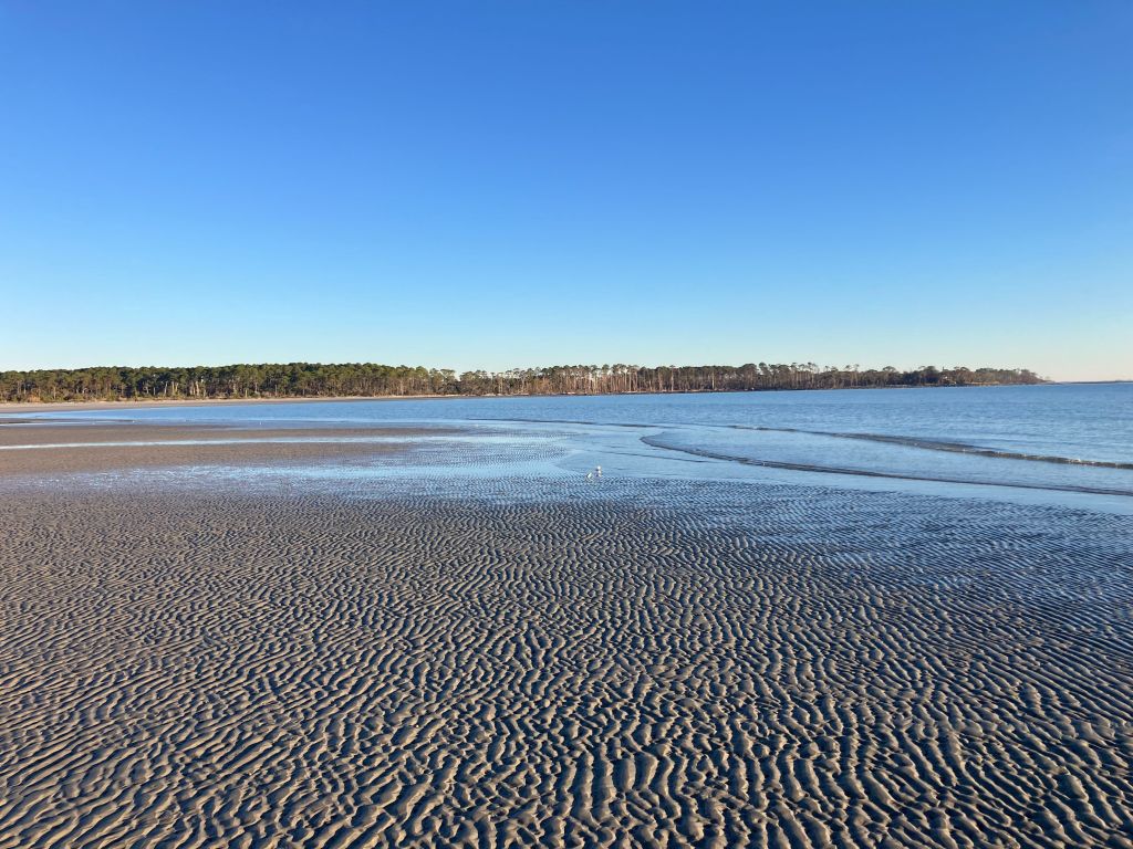 Wet sand flats reflecting the sky