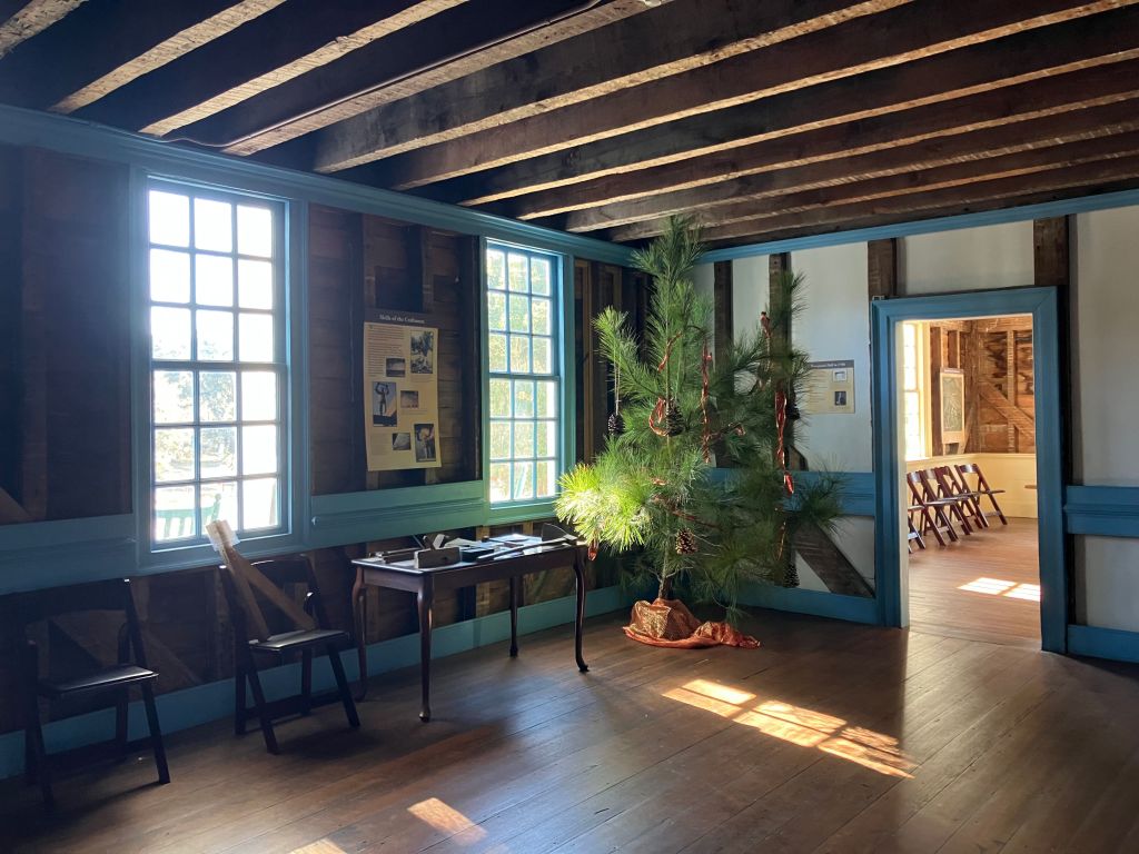 The Long Room with a beamed ceiling, blue trim and a decorated tree