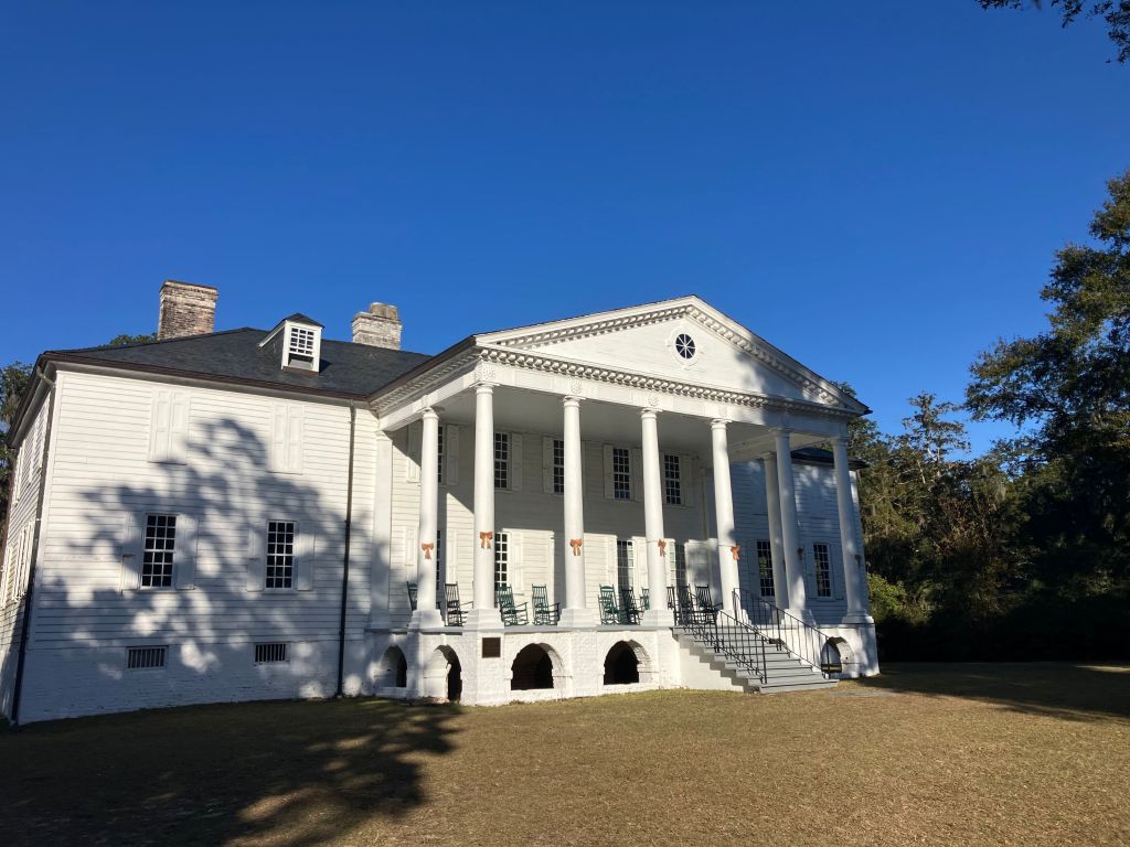 The white Hampton Plantation house with its columned portico under a blue sky