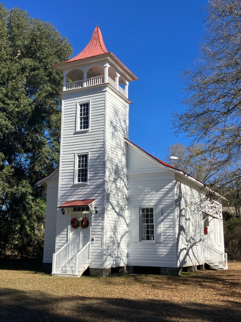 Side view of the white Pineville Chapel and its bell tower