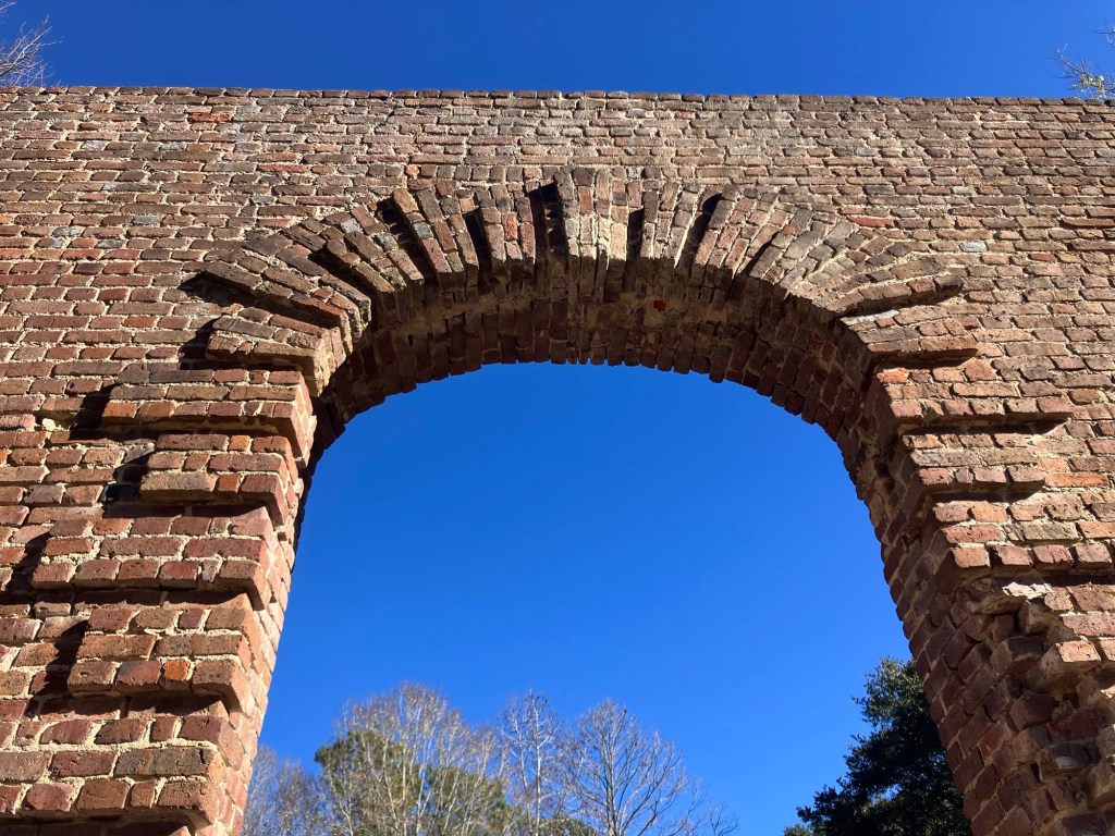 Brick arch of the Biggin Church ruins against a blue sky