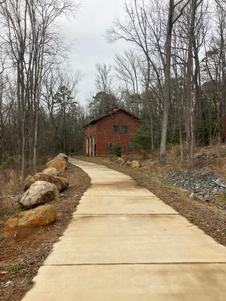 Paved path leading to the brick Arc Building through winter woods