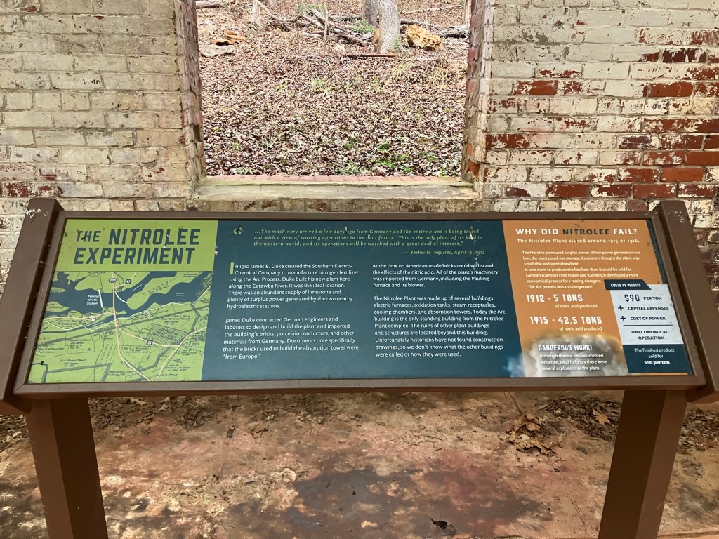 Interpretive panel titled The Nitrolee Experiment in front of the brick building